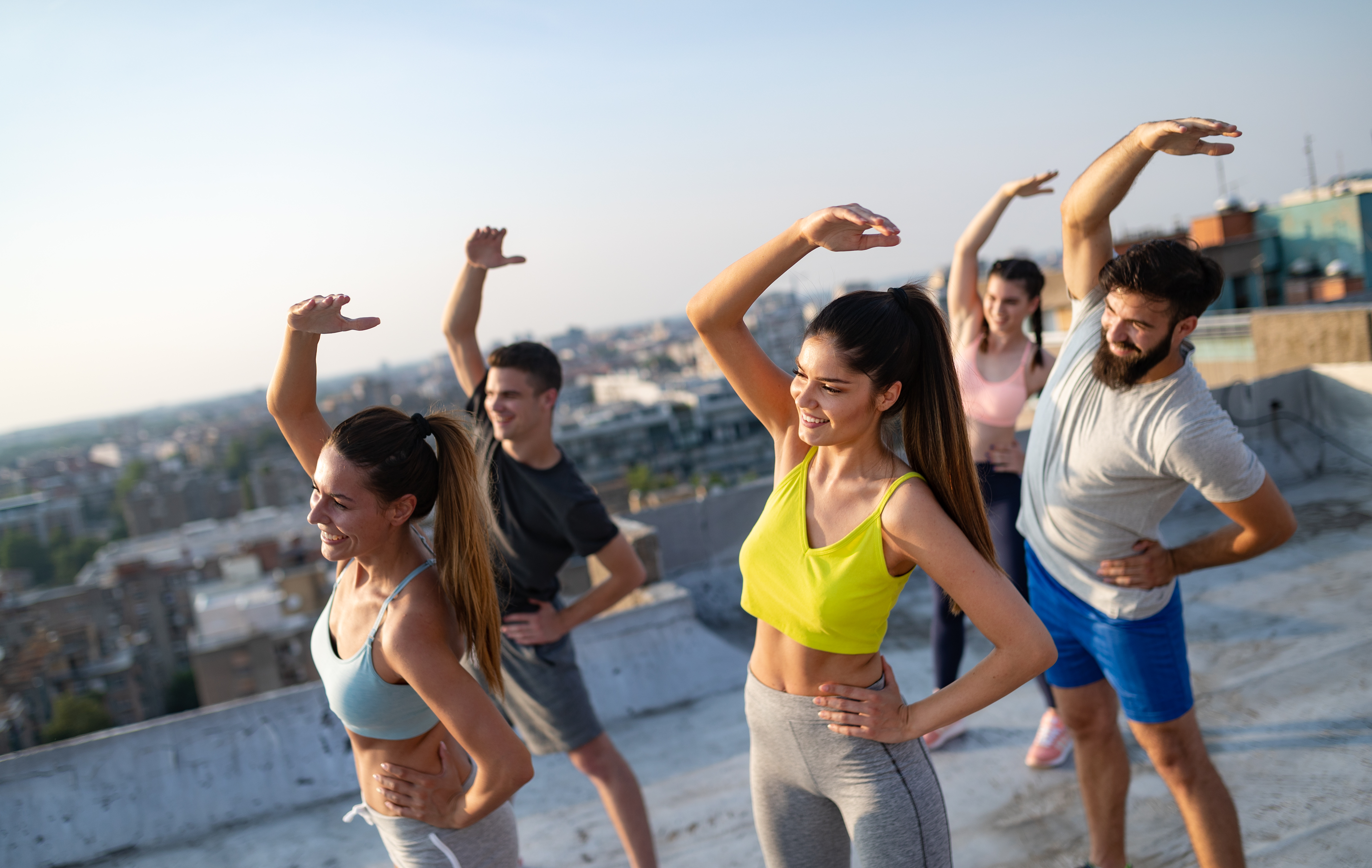 Grupp ta 'ħbieb żgħażagħ tajbin kuntenti li jitħarrġu barra mat-tlugħ ix-xemx